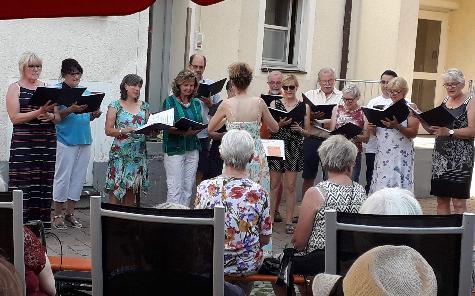 Mit seiner Sommerserenade bereitete der von Jana Müller dirigierte Gemischte Chor den Bewohnern des BRK Seniorenheims St. Barbara, ihren Angehörigen und Freunden einen gelungenen Abend. Hans Meindl (hinten 3.v.r.) lockerte die Liedvorträge mit heiter-nachdenklichen Geschichten auf. - Foto von Werner Schulz