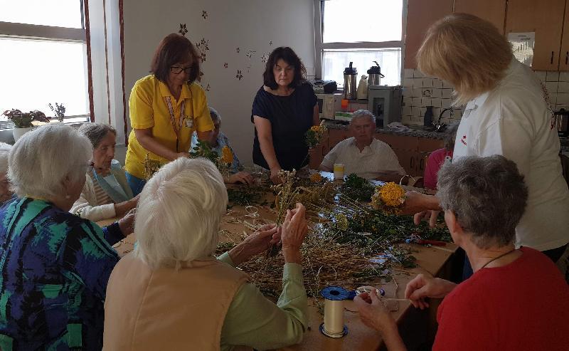 Im BRK-Seniorenheim St. Barbara pflegt man alle Jahre anlässlich des Feiertags Mariä Himmelfahrt, dem Patroziniumstag der Stadtpfarrkirche, die Tradition des Kräuterbüschelbindens. Dabei arbeiten die Seniorinnen und Senioren nicht nur eifrig mit. Sie tauschen zugleich Erinnerungen an den Brauch aus ihrer Kindheit und Jugend aus. Stehend im Bild v. l.: Betreuerin Annemarie Paa und die ehrenamtlichen Helferinnen Lydia Meyer und Maria Maier. - Foto von Werner Schulz