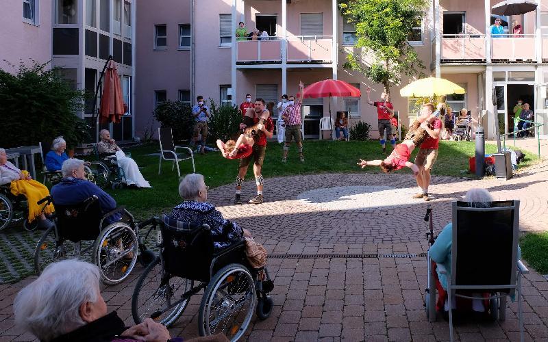 Auf Einladung des Förderkreises Altenhilfe gastierten die Burschen vom Neidaffer Plattlclub in der Gartenanlage des BRK Seniorenheims St. Barbara. Für ihre teils akrobatischen Darbietungen bekamen sie tosenden Beifall, z.B. als der Jackl den Kordl (l.) und der Hias den Dammer (r.) zu „Hulapalu“ von Andreas Gabalier (gemimt vom Beda, kariertes Hemd) durch die Luft kreisen ließen. Mit im Bild: Moderator „Fonse“ (rotes Shirt mit Mikrophon) - Foto von Werner Schulz