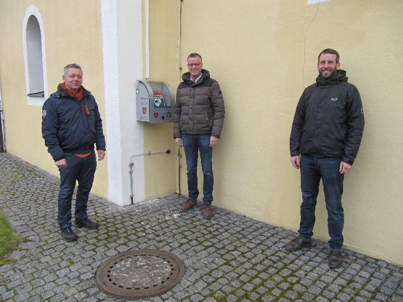 Schnelle „Erste Hilfe“ kann der neue, an der Nordseite der Weiherer Dorfkirche angebrachte Defibrillator im Notfall darstellen. Ortssprecher Georg Ott, links, freut sich mit 1.Bürgermeister Hermann Falk und dem Vorsitzenden der Freiwilligen Feuerwehr Weiher Michael Reif rechts über den Defibrillator. - Foto von Gerhard Fleischmann