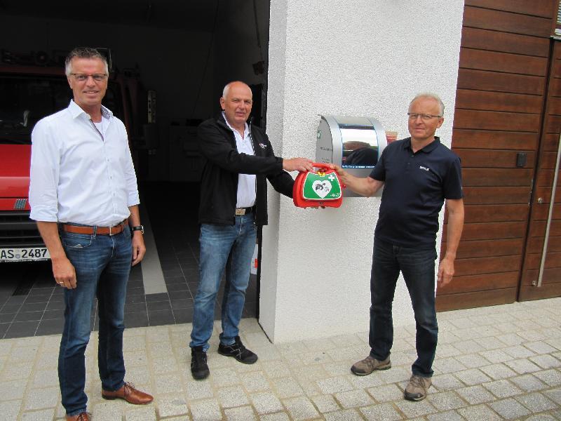 Der Leiter des Rettungsdienstes des BRK Amberg-Sulzbach übergibt der Defibrillator an Ludwig Fischer, den Kommandanten der FFW Steiningloh-Urspring in Anwesenheit von 1.Bürgermeister Hermann Falk. - Foto von Gerhard Fleischmann