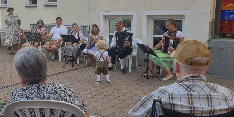 Dieter Kohl (2.v.r.) und seine „Höidlbrumma“ boten den rund 70 Zuschauern beim Bayerischen Abend im BRK Seniorenheim St. Barbara ein Musikprogramm ganz nach deren Geschmack. Für Heiterkeit sorgte der kleine Jakob mit seinen Anweisungen an die Musikant*innen. Stehend l.: Heimleiterin Astrid Geitner. - Foto von Werner Schulz