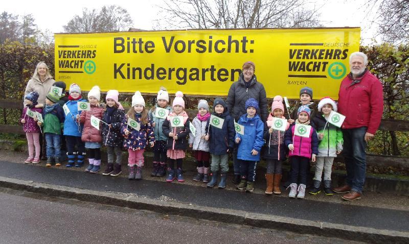 „Bitte Vorsicht – Kindergarten!“ - mahnt ein neues, grell leuchtendes, am Zaun des St. Wolfgang-Kindergartens angebrachtes Transparent, das an die Autofahrer appelliert, den Fuß vom Gas zu nehmen. V. l.: Kita-Leiterin Uta-Maria Kriegler, Kita-Mitarbeiterin Martina Dolles und Verkehrswachtvorsitzender Hubert Ritz. - Foto von Werner Schulz