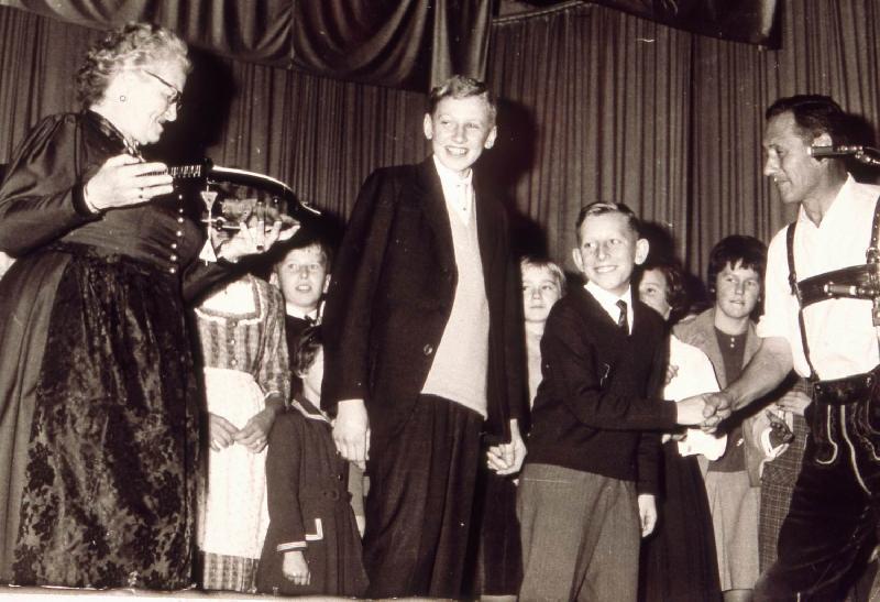 Mit den Liedern „He Michl“ und dem Schnodahüpfl „Dou hint san ma vira“ gewannen die „Hirschauer Boum“ Heiner Schuster (l.) und Werner Schulz (r.) am 13. Oktober 1963 den 1. Preis beim 3. Bayerische Kinder- und Jugendsingen. Als Siegerpreis überreichte Annette Thoma (l.) eine Zither. Außerdem gratulierte Radio- und Fernsehmoderator Wastl Fanderl (r.). - Foto von Strobl (Archiv)