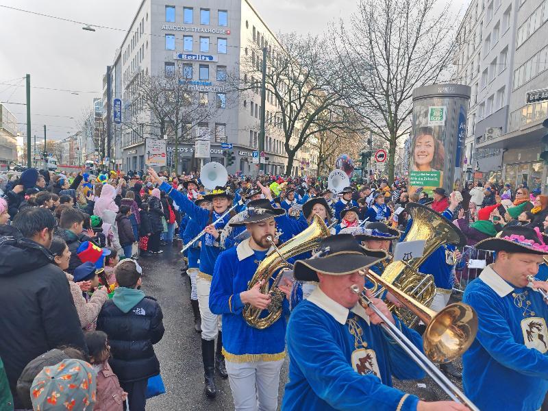 Werner Stein (vorne) ist der absolute Düsseldorf-Rosenmontags-Veteran des Musikzugs. Zum 44. Mal war er heute mit dabei. Zum 13. Mal marschierte er als Standartenträger vorneweg. Schließlich kennt er den Weg schon auswendig. Hinter ihm die drei Majoretten und Dirigent Marcus Hoffmann mit seinen Musikern und Musikerinnen.(Bild Musikzug) - Foto von Werner Schulz