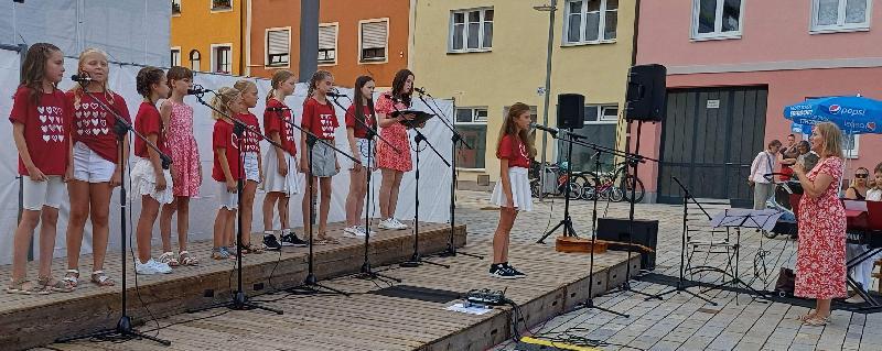 Der „Sommer machte Super-Laune“ beim Konzert des Kinderchors  „Herzwärts“. Von links: Wanda Weiß, Laura Biel, Mia Oberhell, Julia Schinabeck, Magdalena Rauscher, Anna Meier, Romy Weiß, Josephine Summer und Carolina Luber, am Mikro Alisa Graf, rechts vorne: Chorleiterin Gertrud Siegert - Foto von Werner Schulz