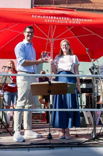 Julius Geiger, der Leiter musikalische Bildung beim Nordbayerischen Musikzug, überreichte an Bürgermeisterin Beate Dietrich die Ehrenplakette und Urkunde „Landmusikort des Jahres 2026“, verliehen vom Deutschen Musikrat und vom Bundesverband Chor & Orchester. - Foto von Michael Knietsch